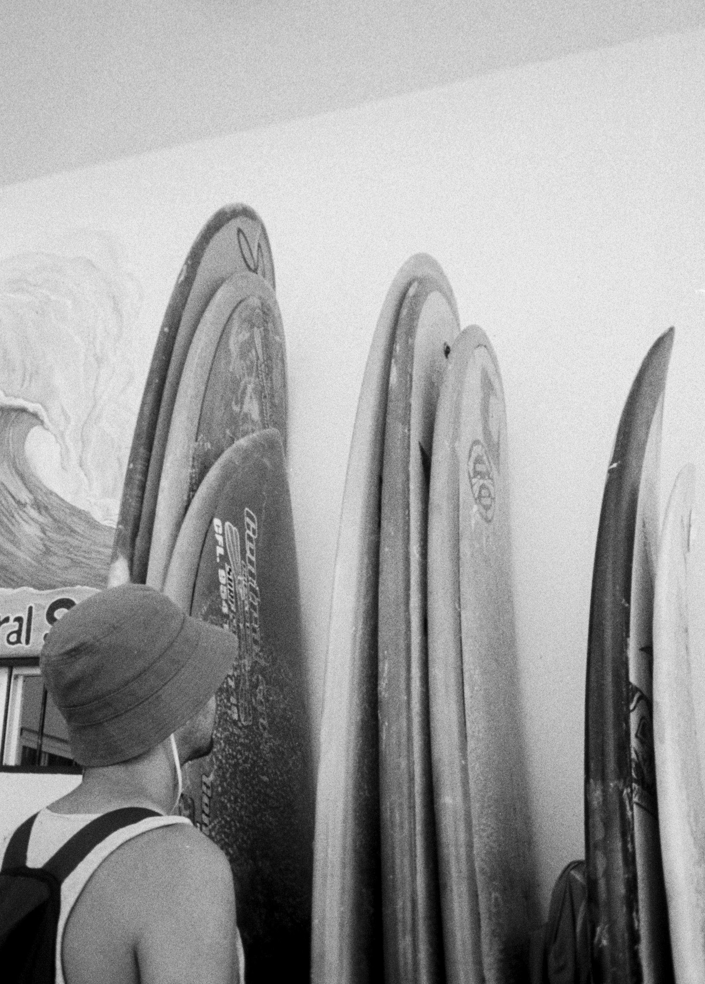 bland and white picture of Diego looking at surfboards